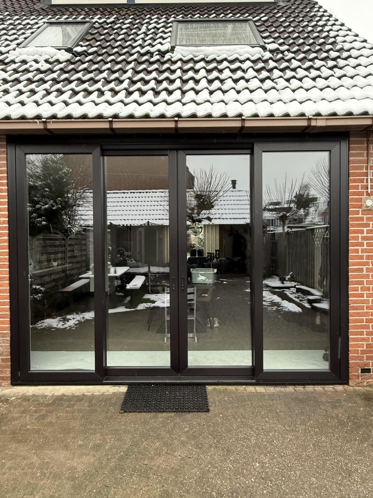 Antraciet openslaande tuindeuren met vaste zijdelen in een aanbouw van rode baksteen
