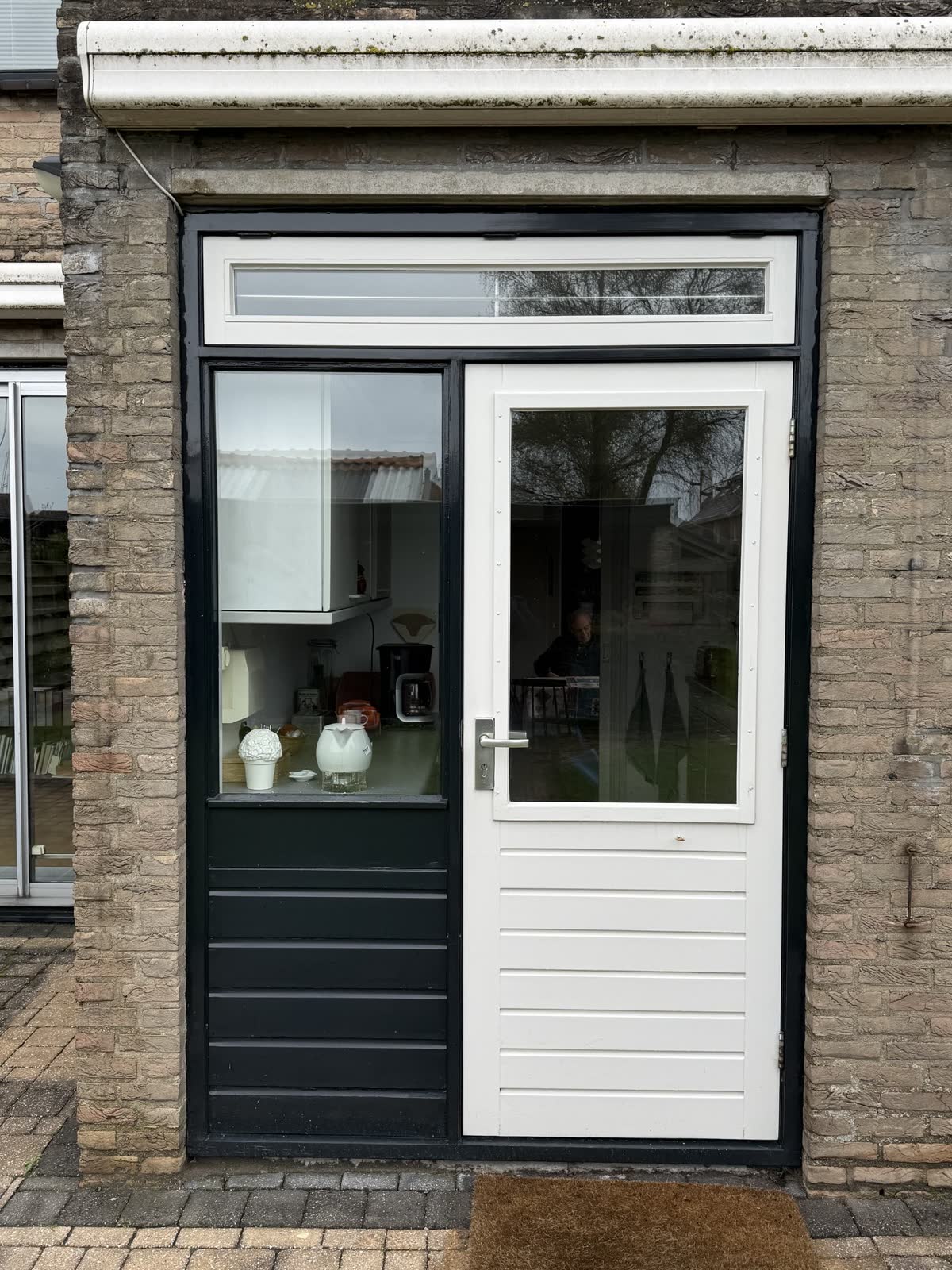 Witte deur met bovenlicht in een donker kozijn