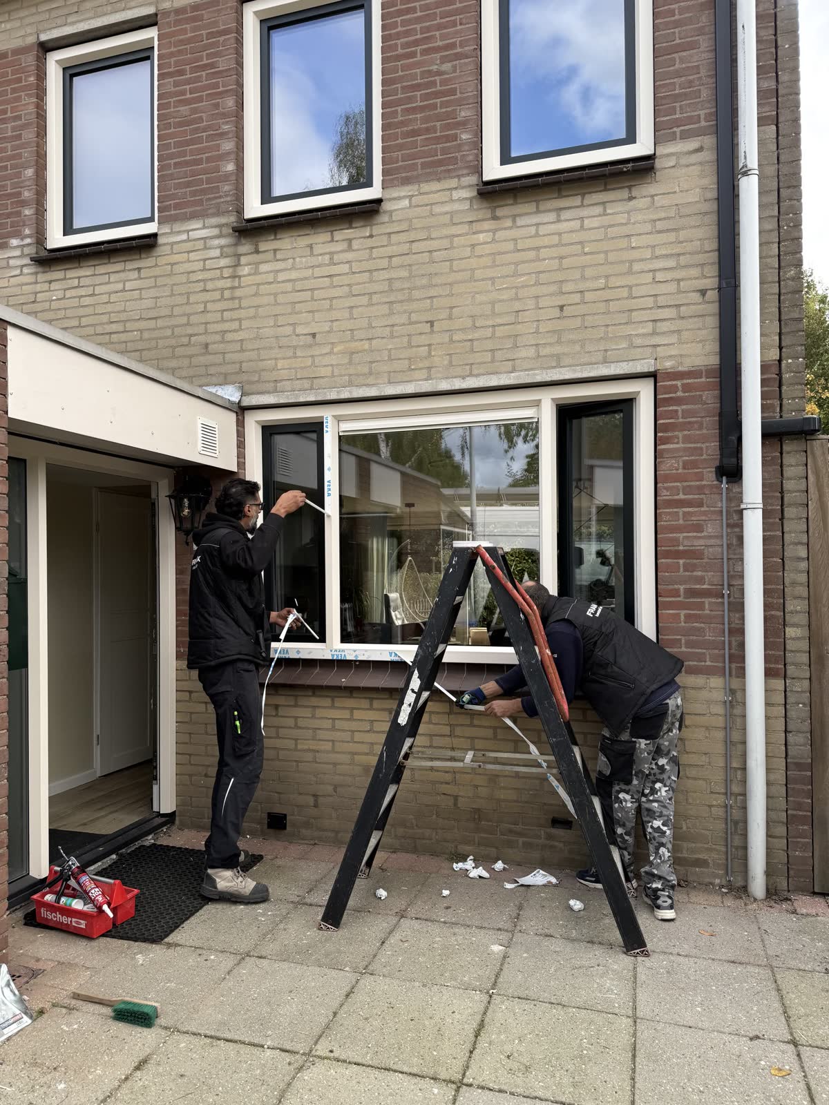 Twee monteurs van Framix werken een nieuw kozijn af in de voorgevel
