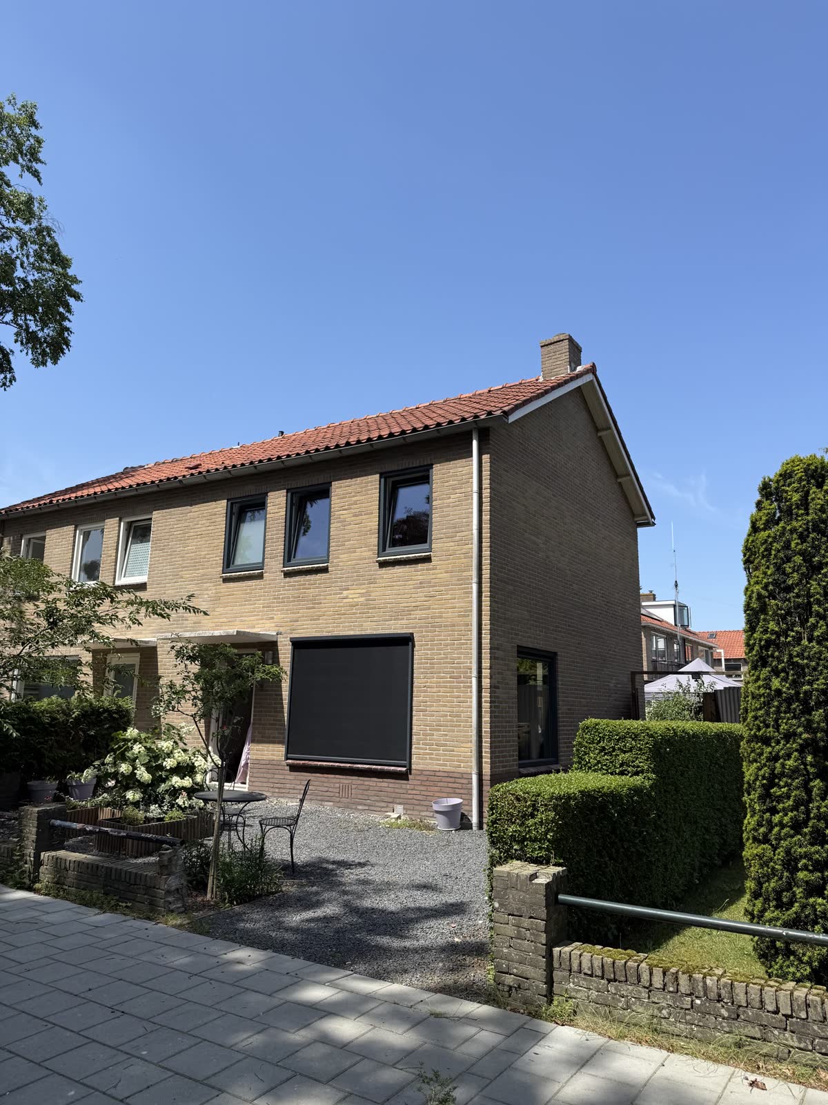 Woning van gele baksteen met nieuwe kunststof kozijnen, onder een blauwe lucht