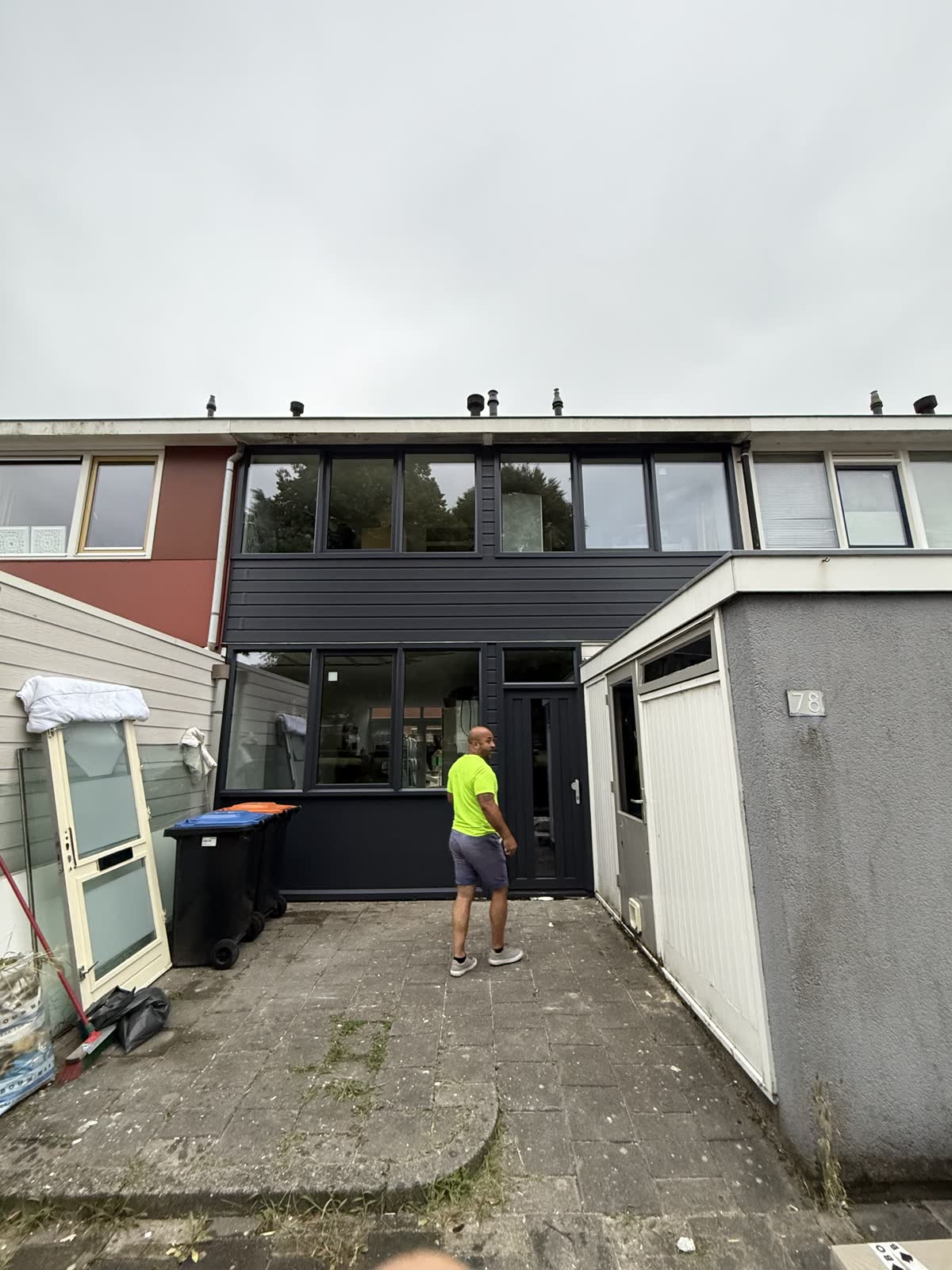 Monteur in een achtertuin, voor een gevel met nieuwe antraciet kozijnen