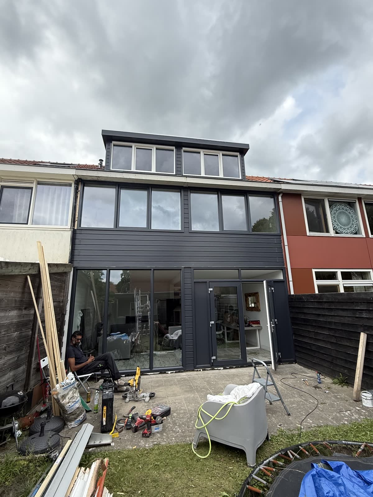 Achtergevel met nieuwe antraciet kozijnen en een glazen pui, tijdens de werkzaamheden
